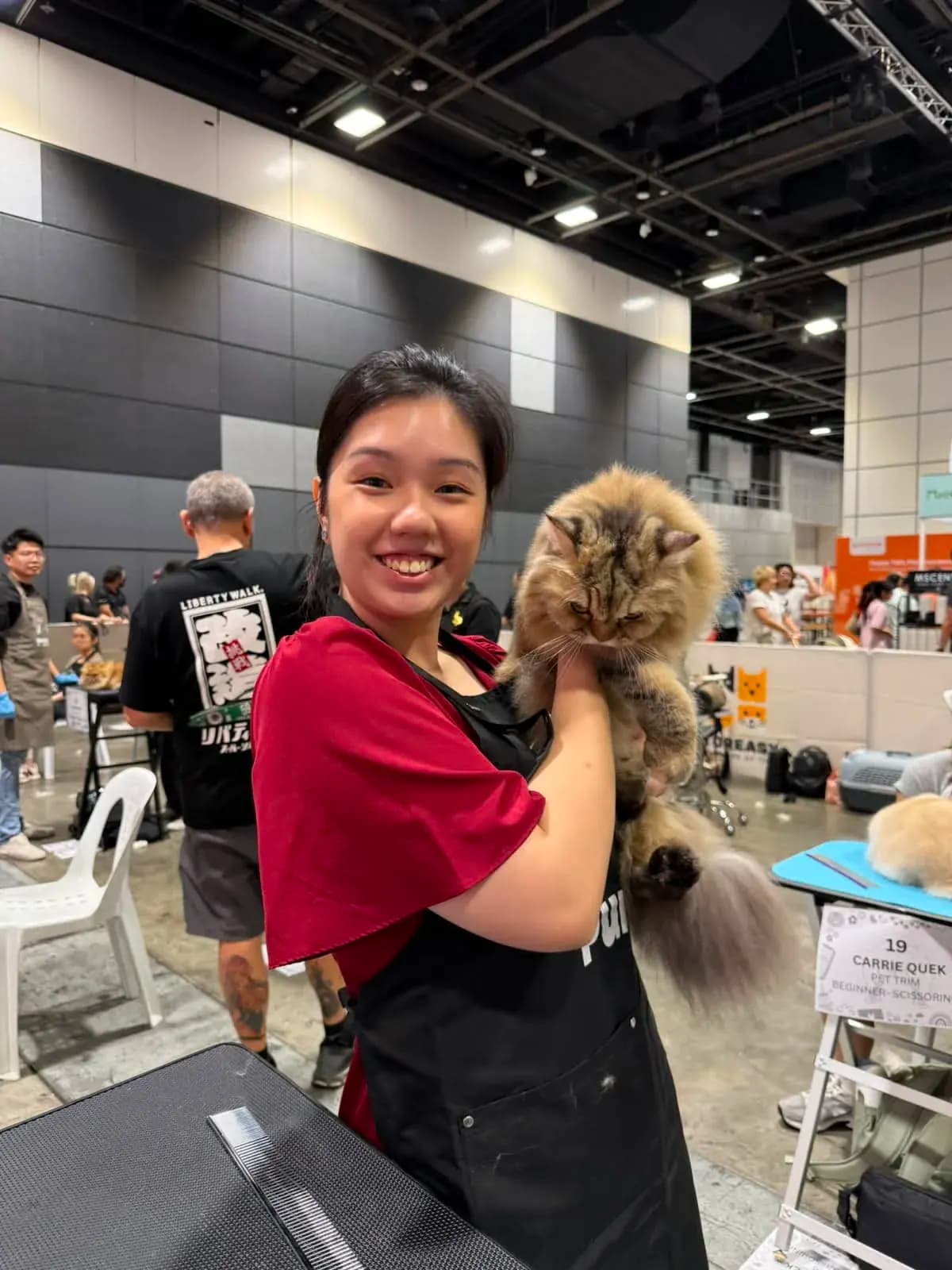 Leah holding a freshly groomed cat at a grooming competition