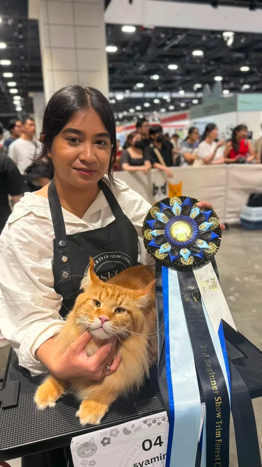 Mimi holding a groomed cat and competition rosette